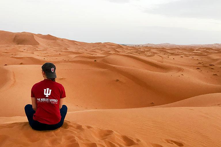 An IU Kelley School of Business student sits in a desert.