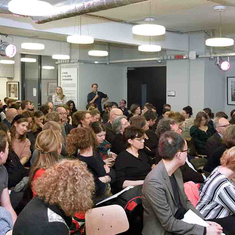 A person with a microphone asks a question of a speaker.