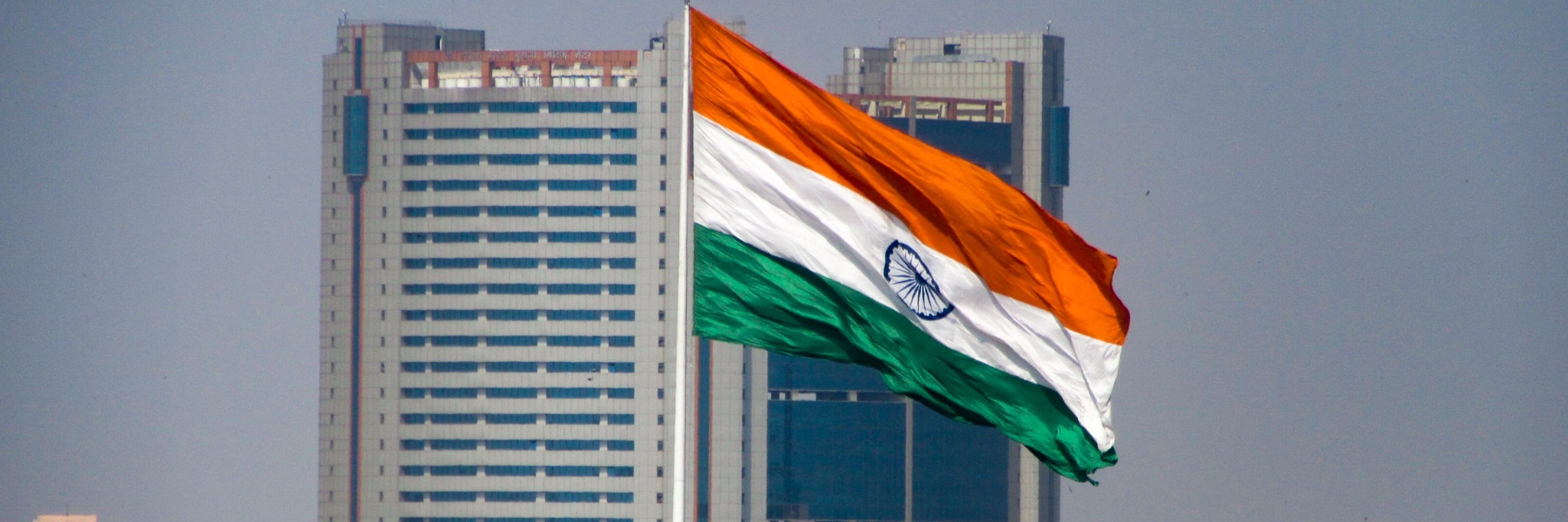 The Indian flag flies in front of two skyscrapers.